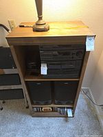 Front view of wooden stereo cabinet with stereo system, speakers and CDs on shelves