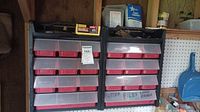 Two black-framed wall storage units with clear front multiple small red drawers filled with various small hardware like screws and nails. Labels on drawers indicate types of contents such as files and chain gauge.