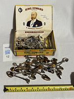 1967 King Edward cigar box containing numerous small vintage collectible silver souvenir spoons, showing the front and inside lid with calendar