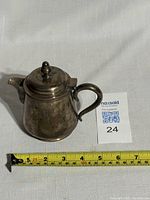 Silver tea pot shown with measuring tape indicating about 4.5 inches in length from handle to spout.