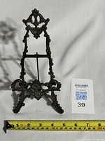 Front view of the ornate brass table easel with a measuring tape showing about 5 inches wide.