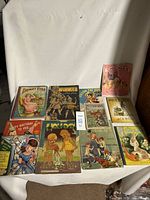 Photo of 12 vintage children's books and 2 vinyl 45 rpm records arranged on a white cloth background showing titles and colorful illustrated covers.