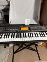 Front view of Roland E-09 keyboard on X-stand with lot tag