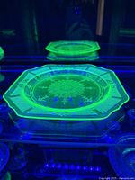 Top view photo showing the uranium glass plate under ultraviolet light, highlighting the green glow of the glass.