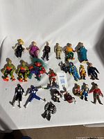 Full lot shot showing all 23 various action figures including characters from California Raisins, Ghostbusters, Beetlejuice, Power Rangers, and others in used condition.