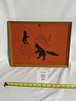 Full view of the framed print showing Inuit hunters, an igloo, and a sled on an orange canvas.