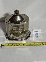 Front angled view of the octagonal vintage silver tea caddy with lid on, showing etched decorative design and scalloped base.