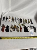 22 Star Wars vintage action figures spread on white cloth with measuring tape at bottom for scale.