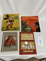 Four vintage children's books laid flat on white surface: Walt Disney's Paint Book, Shirley Temple storybook, 'Here They Are' by Walt Disney, and Uncle Pogo So-So Stories by Walt Kelly.