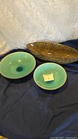 Three ceramic bowls displayed together: two round blue-green glazed bowls (8in and 10in) and one oblong speckled brown decorative bowl.