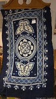 Full view of the rectangular hand-dyed batik textile with large butterfly and floral patterns and embroidered accents.