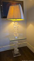 Full view of elegant floor lamp showing the translucent acrylic stacked base, integrated square glass table, fabric lampshade, and ambient light glow.