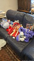 Photo shows yarn skeins, knitting needles, and three knitting projects laid out on a dark leather couch.