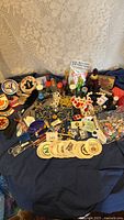 Wide assortment of vintage badges, pins, keychains, patches, small toys, and decorative items on a blue cloth background.