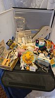Photo of the full lot showing various vintage sewing notions and accessories inside a suitcase and box.