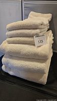 Stack of cream-colored plush towels including both bath and hand towels folded neatly.