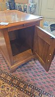 Photo shows side table with cupboard door open revealing empty interior storage space and a pull-out shelf extended.
