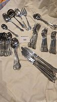 Full overview of the stainless steel cutlery set laid out on cloth, showing all types of utensils in matching pattern.