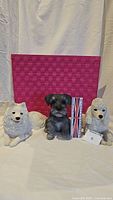 Three medium dog sculptures (schnauzer, samoyed, poodle) displayed together with a pink background and a UK flag box for size reference.