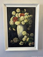 Front view of unsigned chrysanthemum still life oil painting in white frame showing bouquet of yellow and orange flowers in vase.