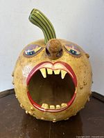 Front view showing the carved open mouth, eyes, nose, and green stem.