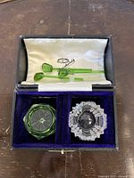 Two cut crystal salt cellars and three green glass spoons in velvet-lined box with satin lid, showing detailed craftsmanship and presentation.