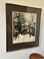 Framed Albert Franck print showing a winter street scene with snow and old houses, viewed frontally.