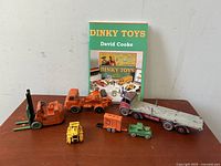 Full lot display with six vehicles and Dinky Toys book in background on wooden table.