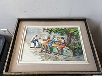Frontal photo of framed watercolour showing four figures on a bench by a harbour, under tree shade, sharing fish from the morning catch
