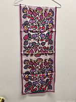 Full view of the scarf hanging on a hanger showing the entire length and design.