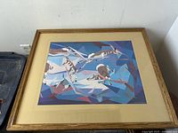 Front angled photo of framed art print showing the styled antelope figures in flight against a geometric background.