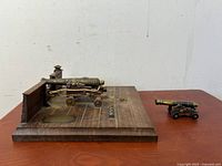 Side view showing wood platform base with one metal model cannon and a smaller metal model cannon next to it