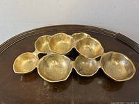 Top view of the signed Zodax metal cluster sculpture showing organic concave pods with a hammered brass finish on a dark wood surface.