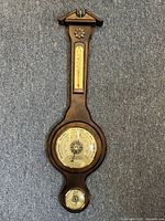 Full view of the vintage wooden banjo-shaped wall barometer showing the thermometer, barometer dial, and hygrometer at the bottom.