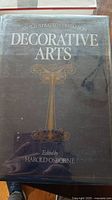 Close-up of book titled 'Decorative Arts' edited by Harold Osborne with visible dust jacket.