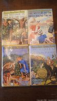 Four Nancy Drew novels covers arranged side-by-side on surface showing title and cover art