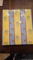 Photo of yellow and blue striped photo album cover with floral patterns