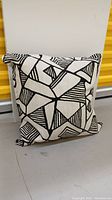 One black and white cushion with bold linear geometric pattern featuring thick and thin black lines on white fabric.