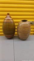 Two lightweight decorative floor vases, one tall and narrow mouth, one shorter with wide mouth, striped earth tone colors