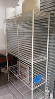 Full view of the white metal wire shelving unit with three shelves inside a storage environment.