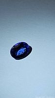 Loose oval cut deep blue-violet tanzanite gemstone on white background