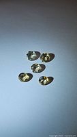 Five loose natural citrine gemstones, round cut, about 5mm size. Displayed on flat surface with some shadowing from lighting.