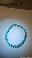 Natural turquoise stretchy bracelet laid flat showing round turquoise beads approximately 6mm in diameter.