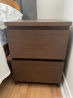 Photo of one wood veneer bedside table showing front view with two drawers, flat panel fronts, and modern rectangular design.