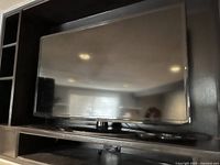 Samsung 42-inch TV mounted within a black shelving unit, showing the screen and surroundings from the front angle.