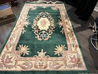 Green wool area rug laid out flat showing full pattern and colors
