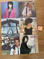 Photo of six vinyl albums arranged in two rows of three on a wooden surface featuring front covers of Billy Joel - Glass Houses, Huey Lewis & the News - Sports, Laura Branigan - Self Control, Rick Springfield - Working Class Dog, Joan Jett and the Blackhearts, and Pat Benatar