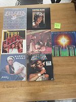 Photo showing seven vinyl albums on a wooden table. The titles and artists are legible and correspond to seller's description.