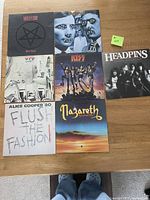 Photo of seven vinyl rock albums arranged on a wood table, showing front covers with used condition visible