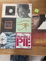 Photo of eight assorted vinyl albums arranged in a 3x3 grid (one empty spot). Albums include Robert Palmer, Robert Plant, Alan Parsons Project, Humble Pie, 38 Special, Spirit, and Jean-Michel Jarre. Covers show photographic portraits, logos, and graphic designs.